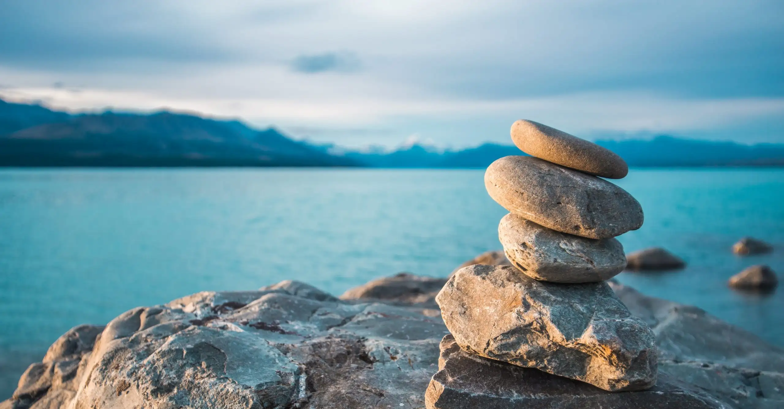 Stones balanced on the shore at dusk, with calm water behind